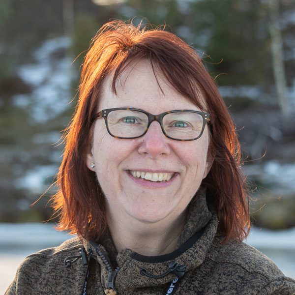 This photo shows Sara Riggare looking at the camera with a blurred background showing trees and snow.